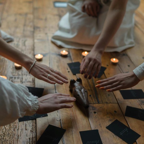 Women gather around candles and cards in a spiritual ritual indoors.